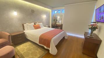A modern bedroom with a large bed, bedside tables, a desk, and a chair.