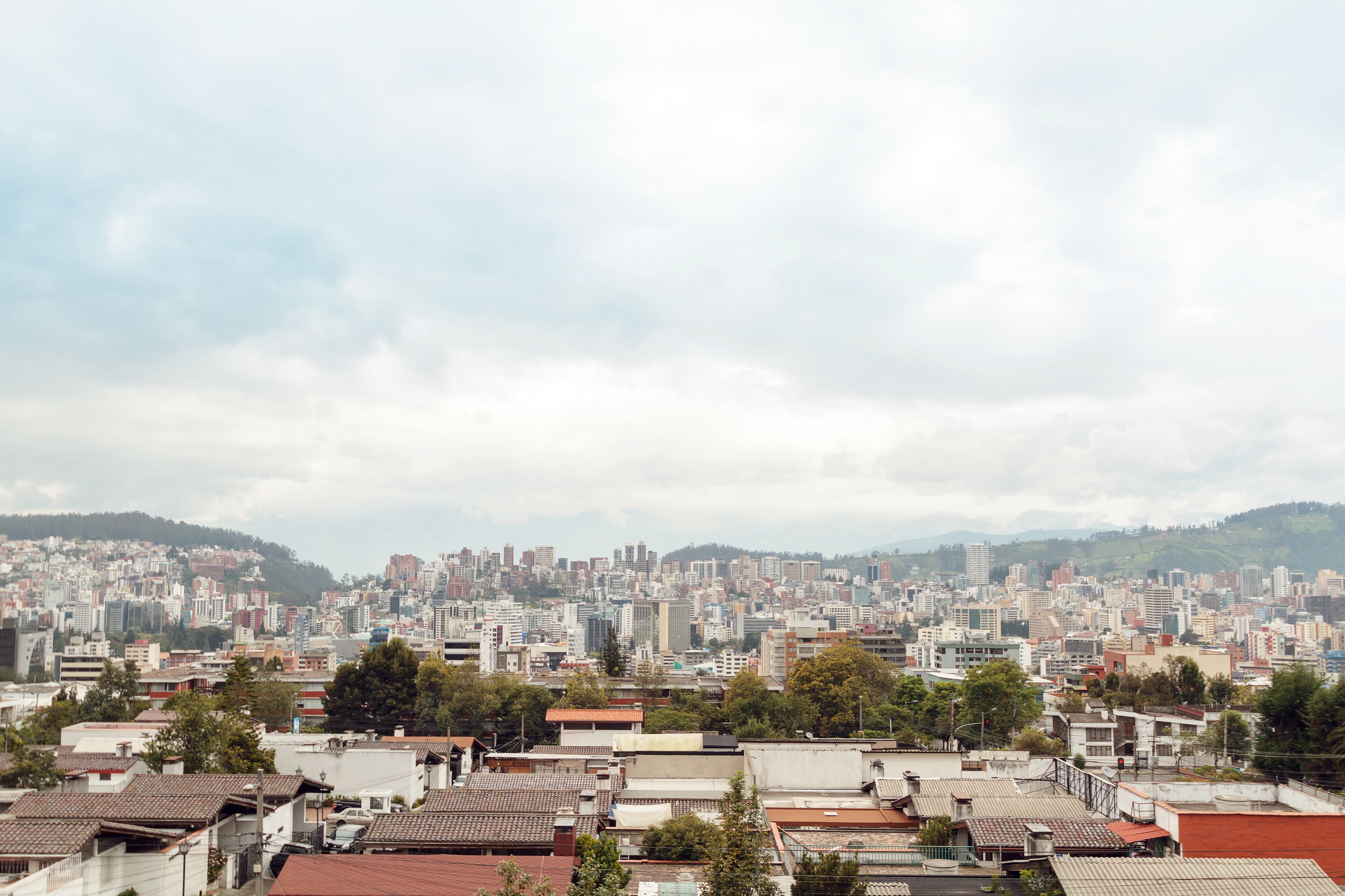 Un paisaje urbano con una zona densa, varios edificios y un fondo montañoso.