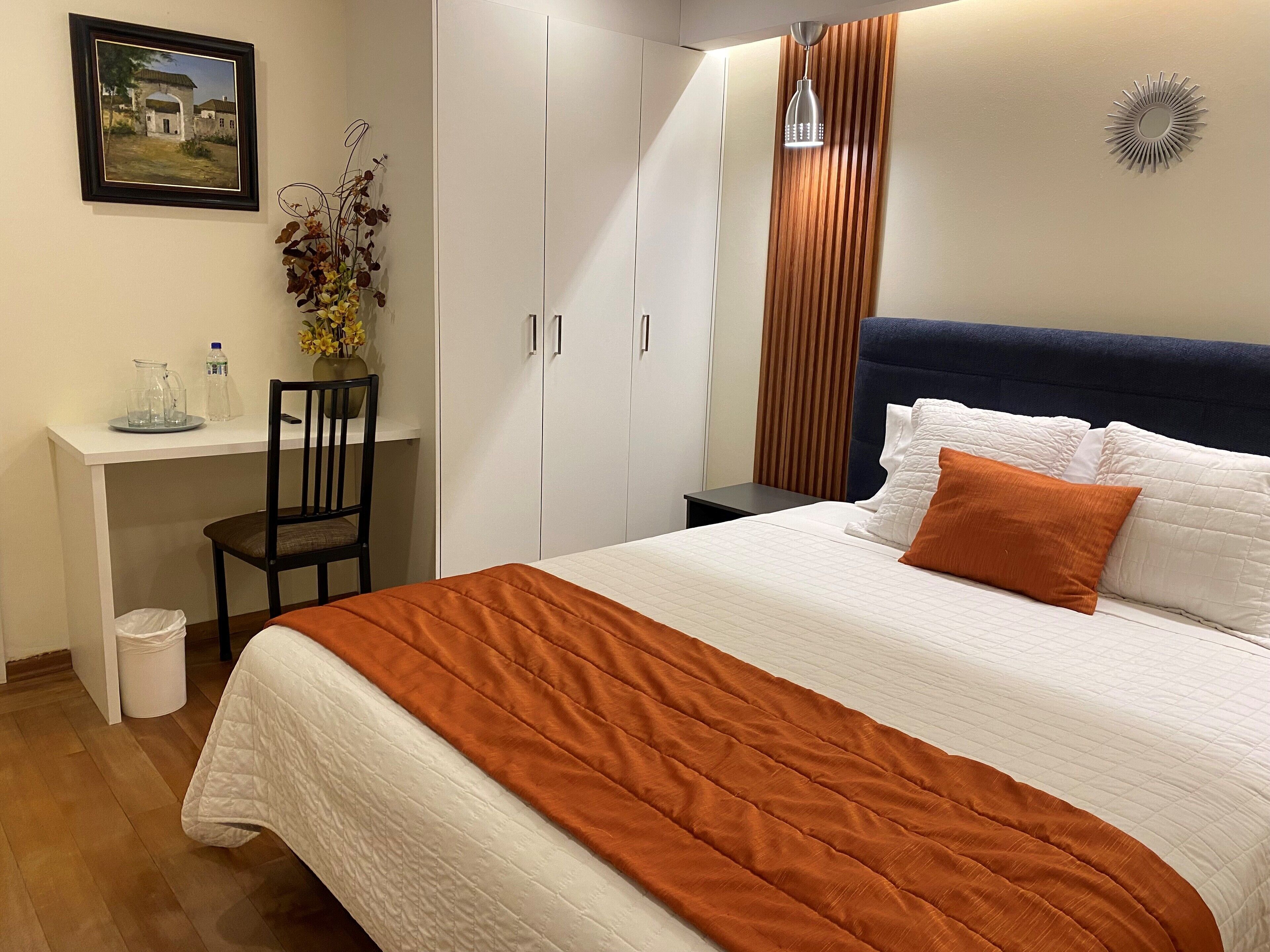 A neatly arranged bedroom with a bed, a desk, and a chair.