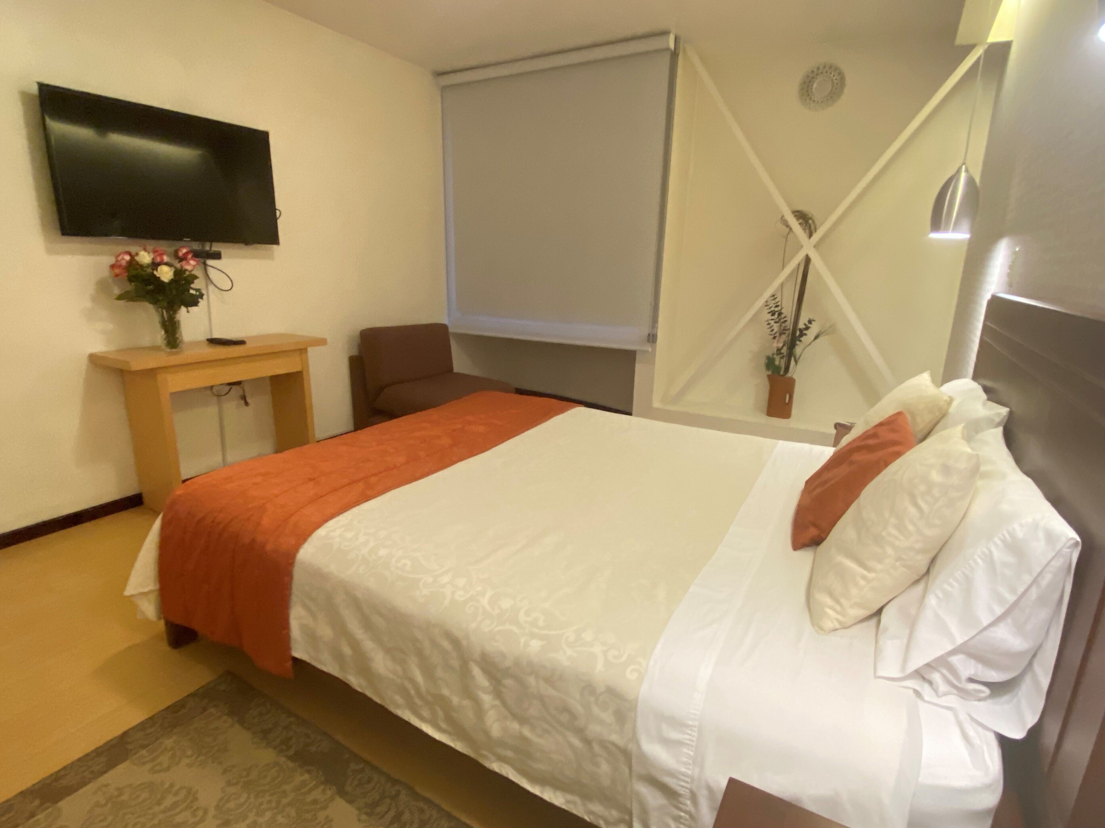 Une chambre d’hôtel avec un lit, une télévision, un bureau et une chaise.