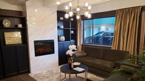 A modern living room with a fireplace, a sofa, a coffee table, and a chandelier.