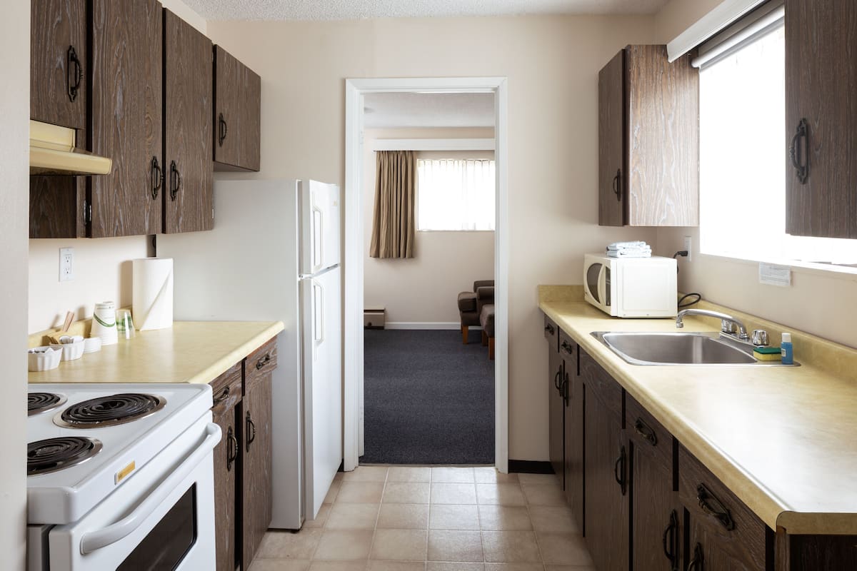 A kitchen with wooden cabinets, a white refrigerator, a microwave, and a sink.