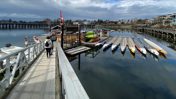 A dock with canoes lined up and a flag on a pole.