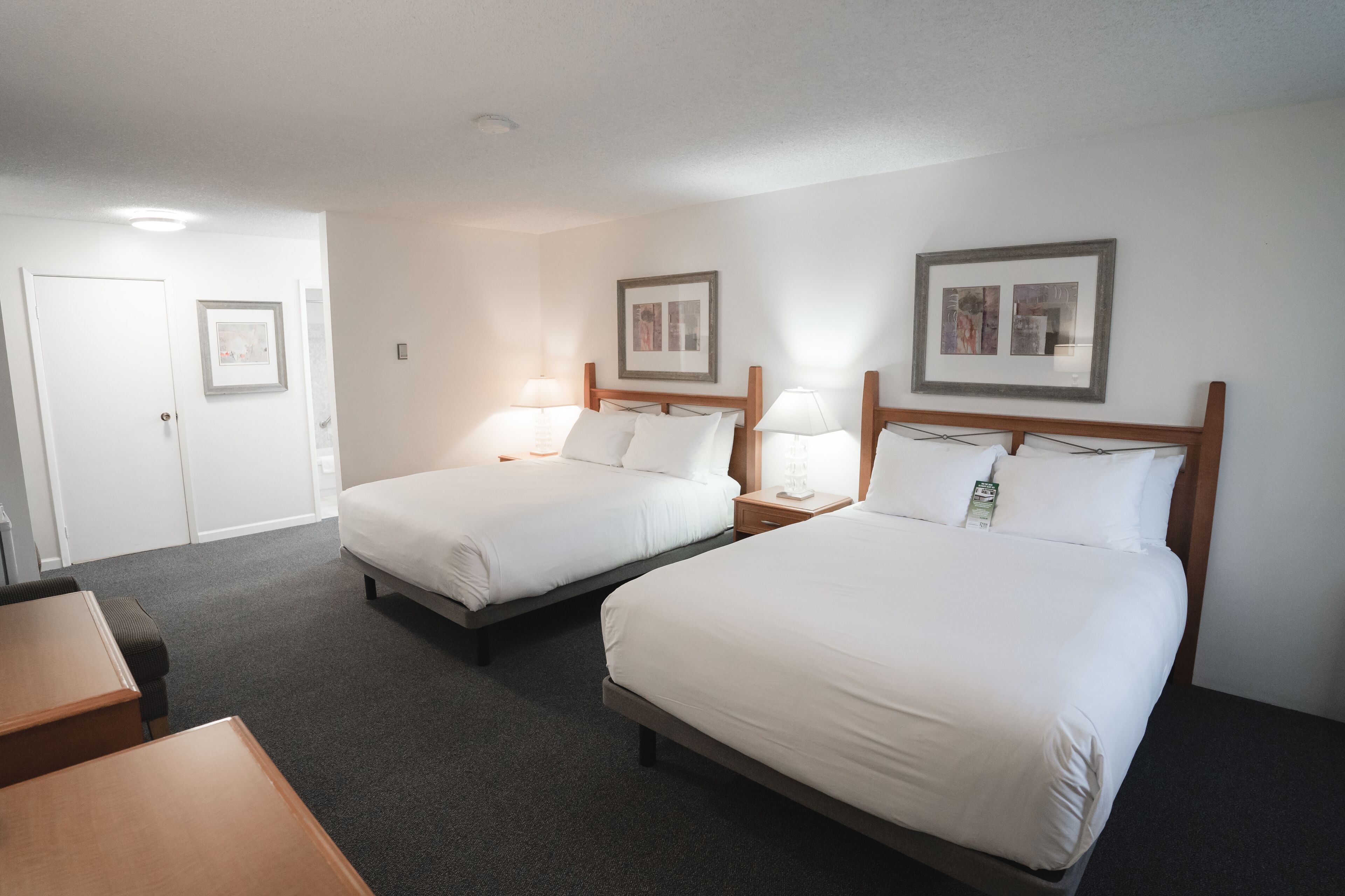 A hotel room with two single beds, a desk, and a chair.