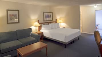 A hotel room with a bed, a sofa, a small table, two bedside lamps, and two framed pictures on the wall.