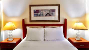 Une chambre d’hôtel avec un lit, deux tables de chevet, deux lampes et un tableau encadré au mur.