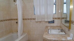 Un baño con bañera, lavamanos, espejo y paredes de azulejos.