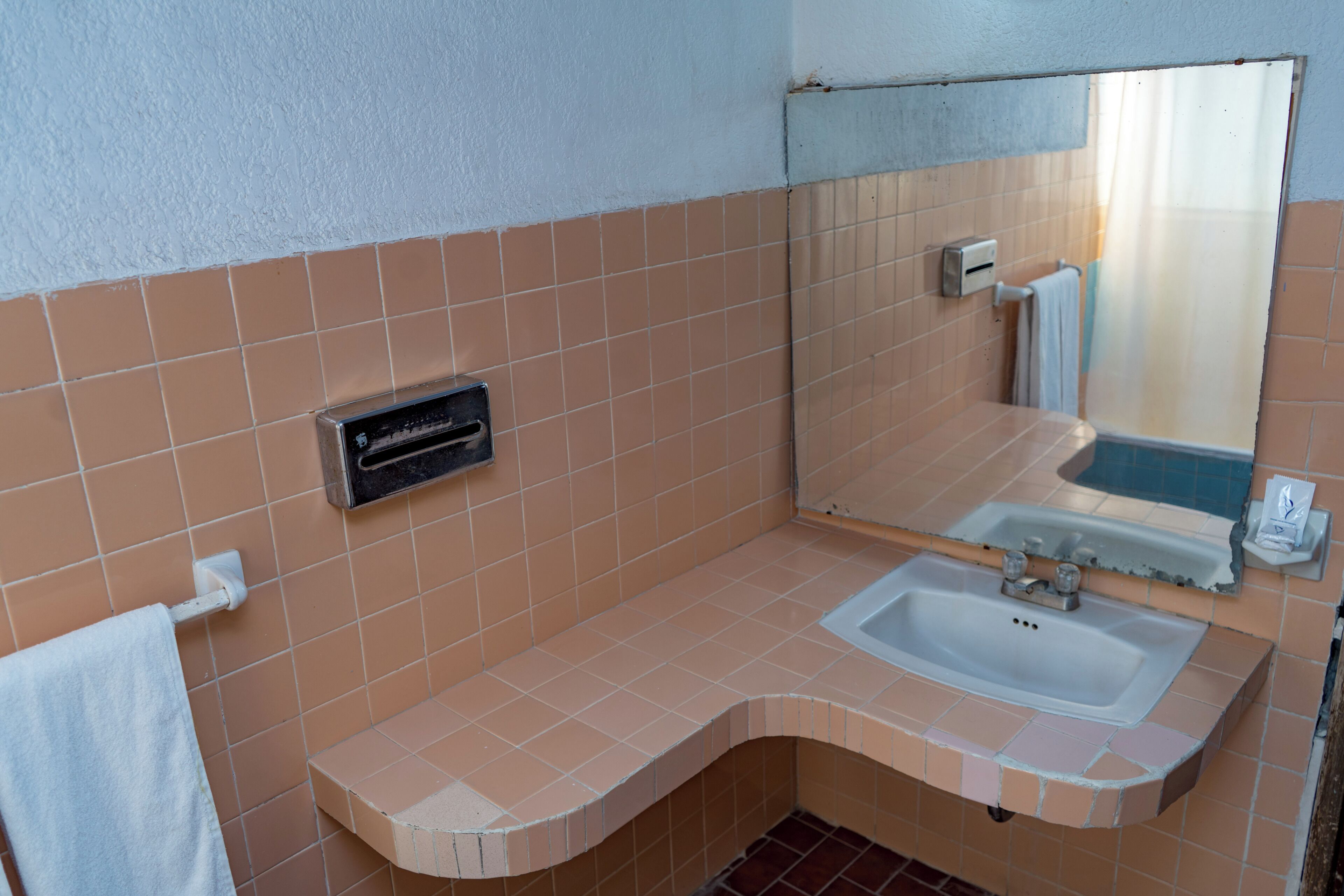 A bathroom with a sink, mirror, towel rack, and a ventilation unit.