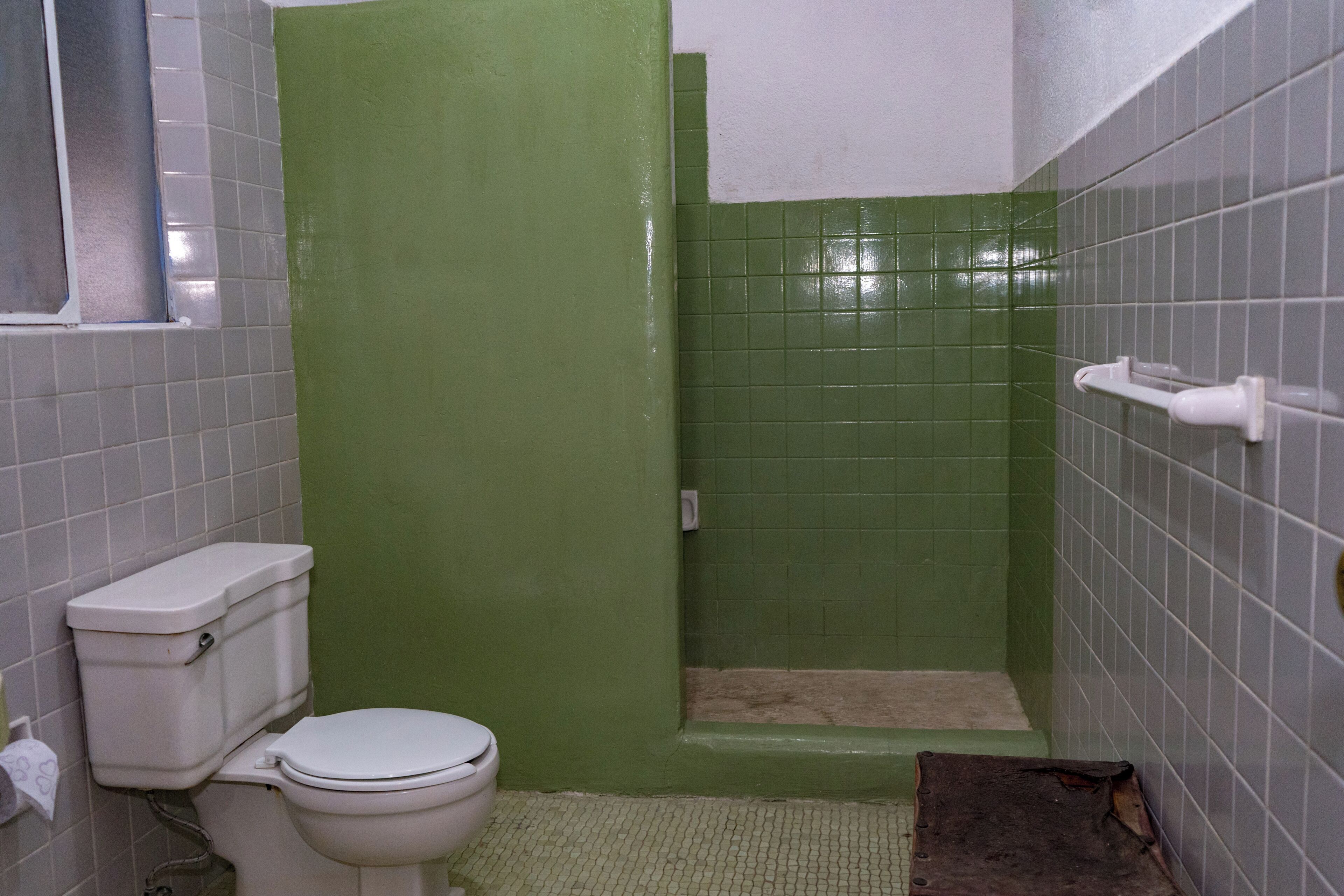 A bathroom with a toilet, green shower enclosure, and tiled walls.