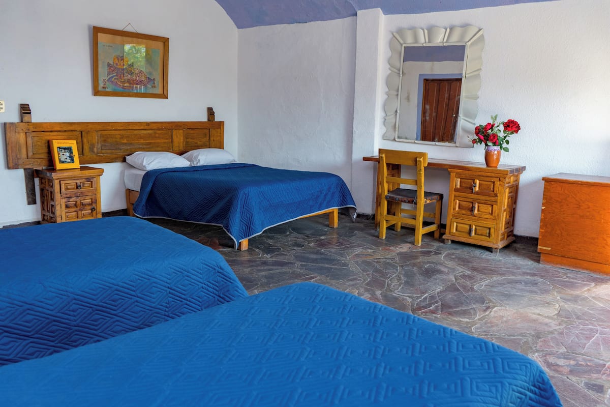 Un dormitorio con dos camas, un aparador de madera, un escritorio, un espejo y una ventana con vistas.