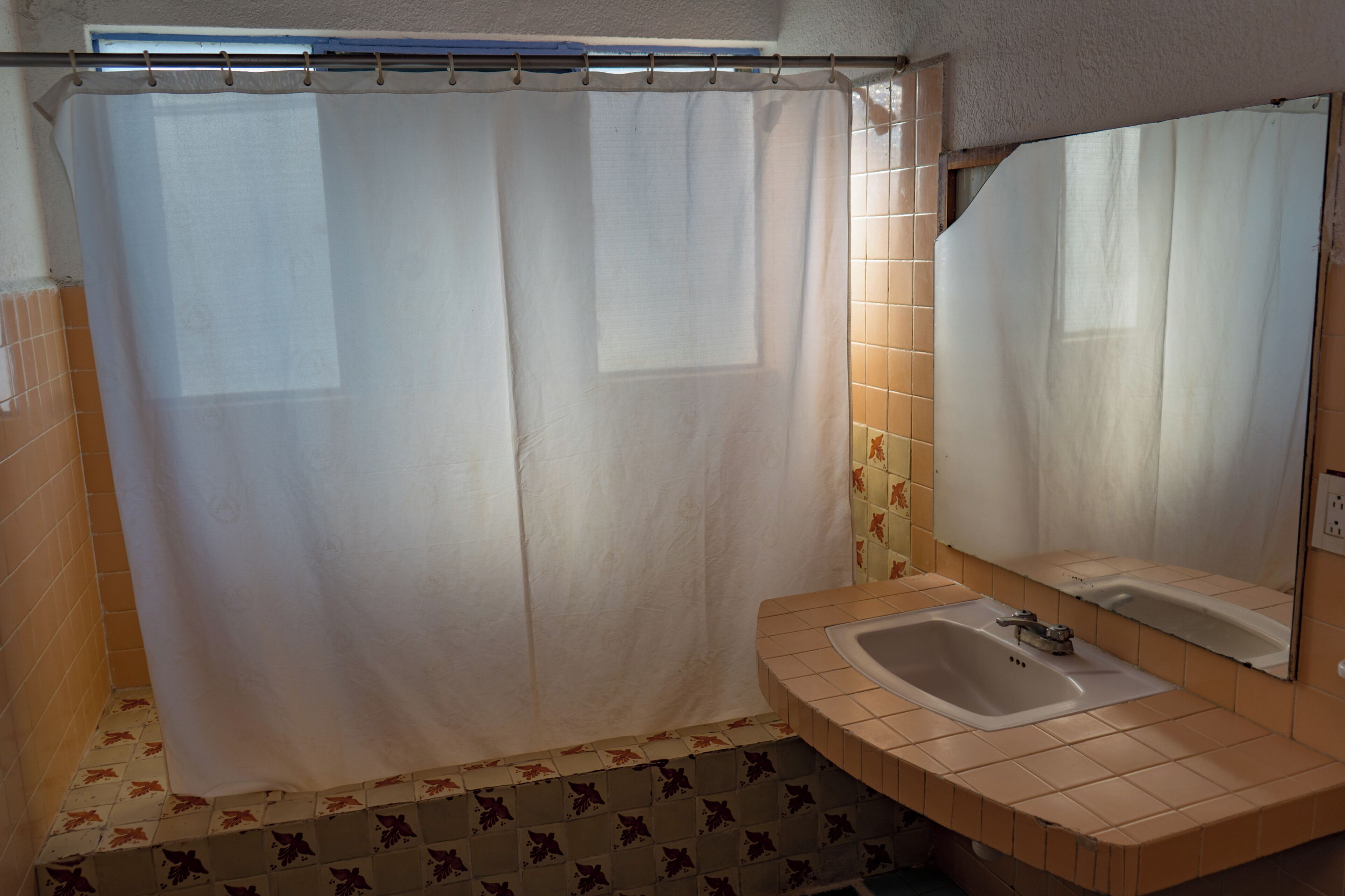 A bathroom with a shower curtain, a sink, and a mirror.