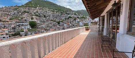 A balcony with a tiled floor and a view of a densely packed hillside town.