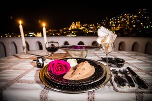 A table set for a meal with candles, a rose, and a city view in the background. - Hotel-Museo Posada de la Misón (Taxco)