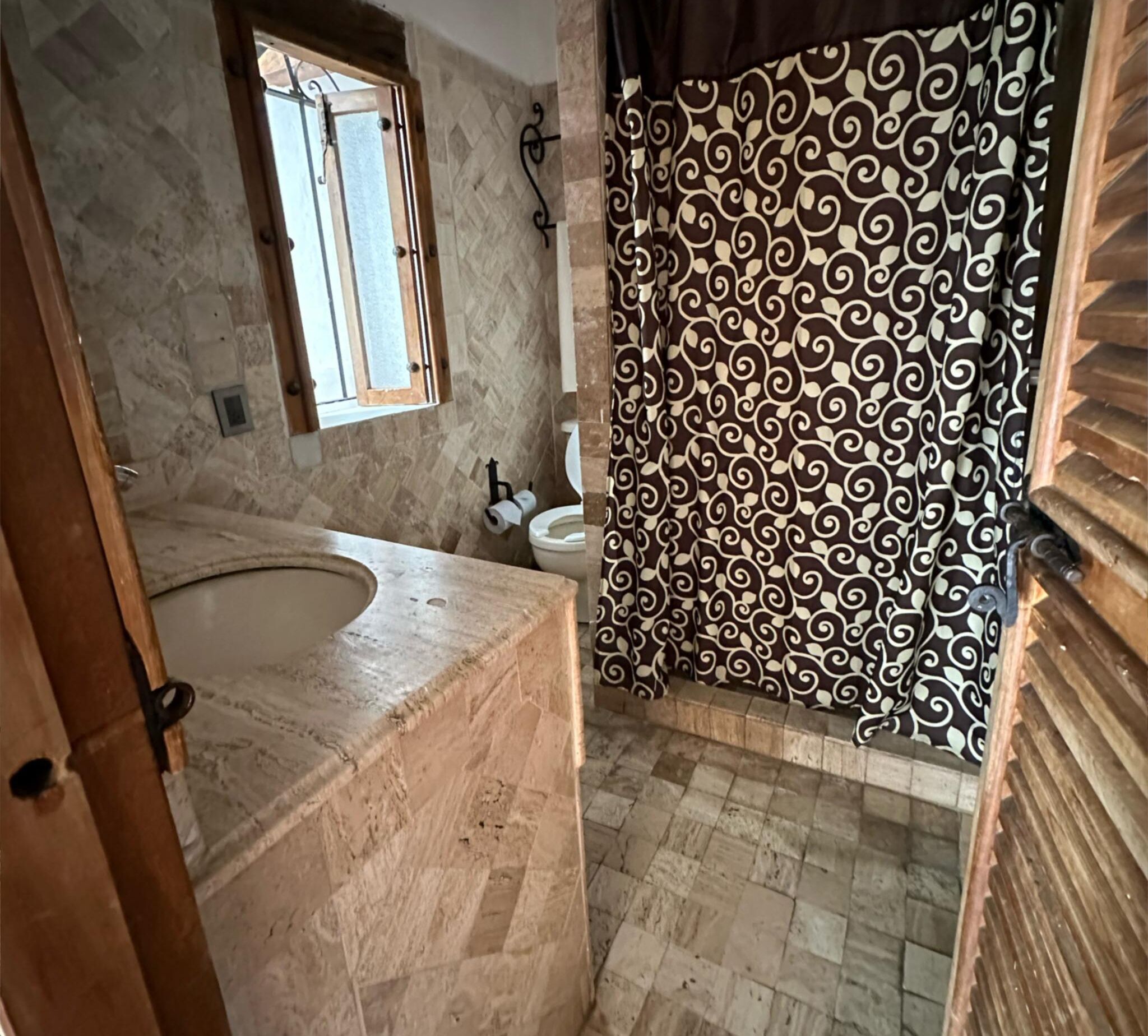 A bathroom with a large bathtub, a toilet, and a shower curtain with a swirling pattern.