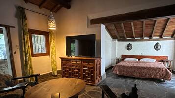 Una stanza accogliente con un letto, una TV, un tavolo di legno e un pavimento in pietra.