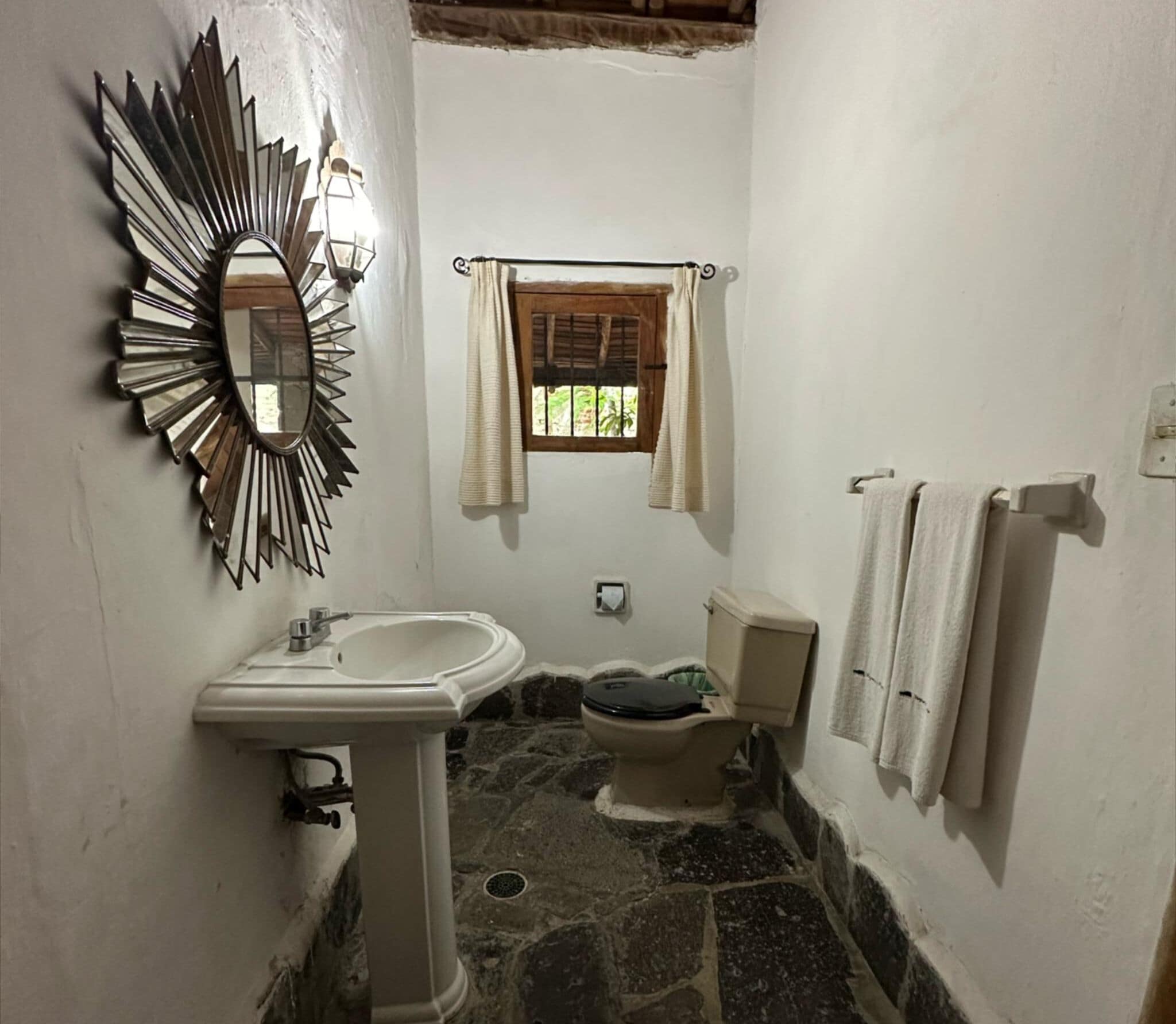 A bathroom with a sink, toilet, and a mirror.