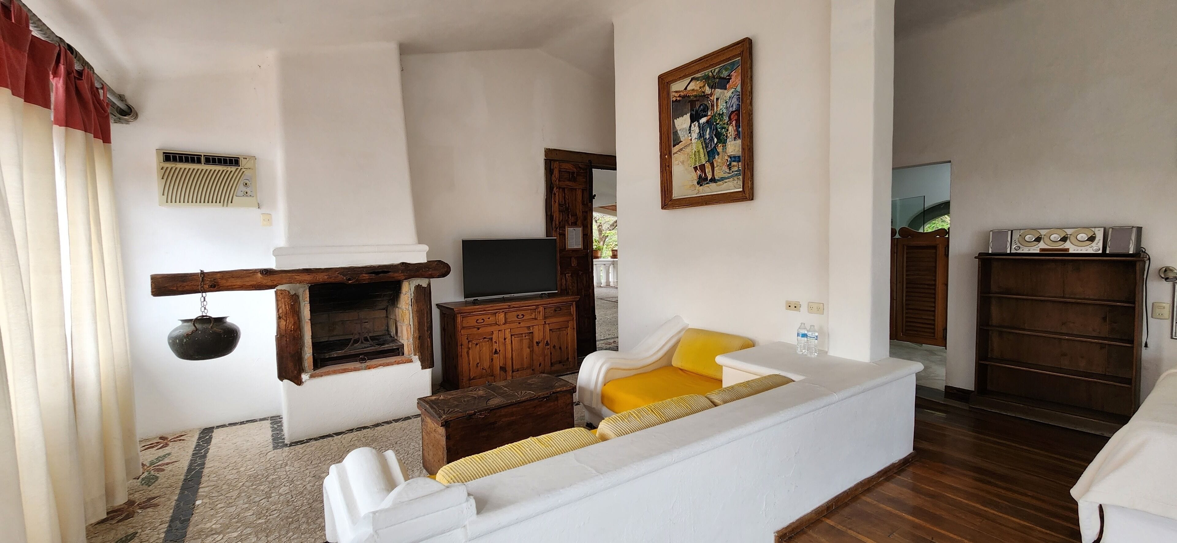 A living room with a fireplace, a television, a sofa, and a painting on the wall.