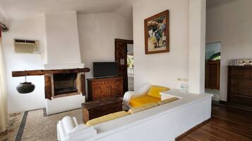 A living room with a fireplace, a television, a sofa, and a painting on the wall.