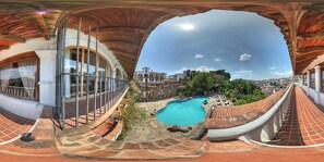 A panoramic view of a rooftop swimming pool with a clear sky, surrounded by terracotta-tiled architecture and a lush green landscape. - Hotel-Museo Posada de la Misón (Taxco)