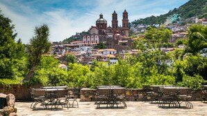 Un patio con mobiliario exterior y vistas a una iglesia histórica con dos campanarios.
