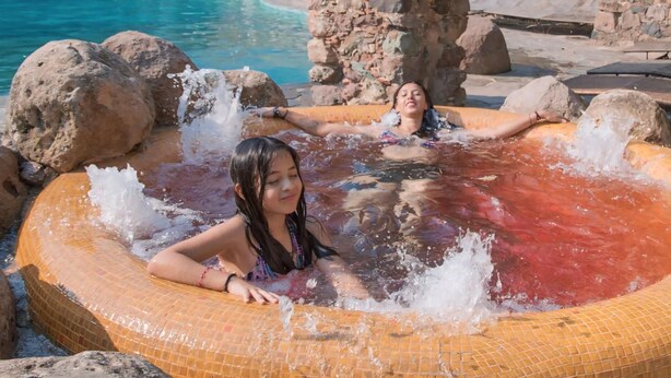 Tinaco con un arco de piedra y una piscina al fondo.