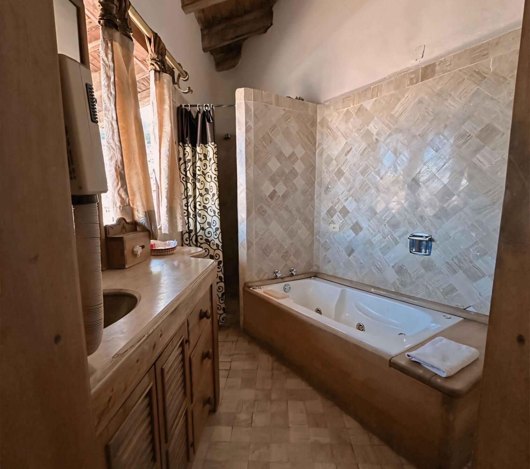 A bathroom with a wooden vanity, a freestanding bathtub, and a patterned tile wall.
