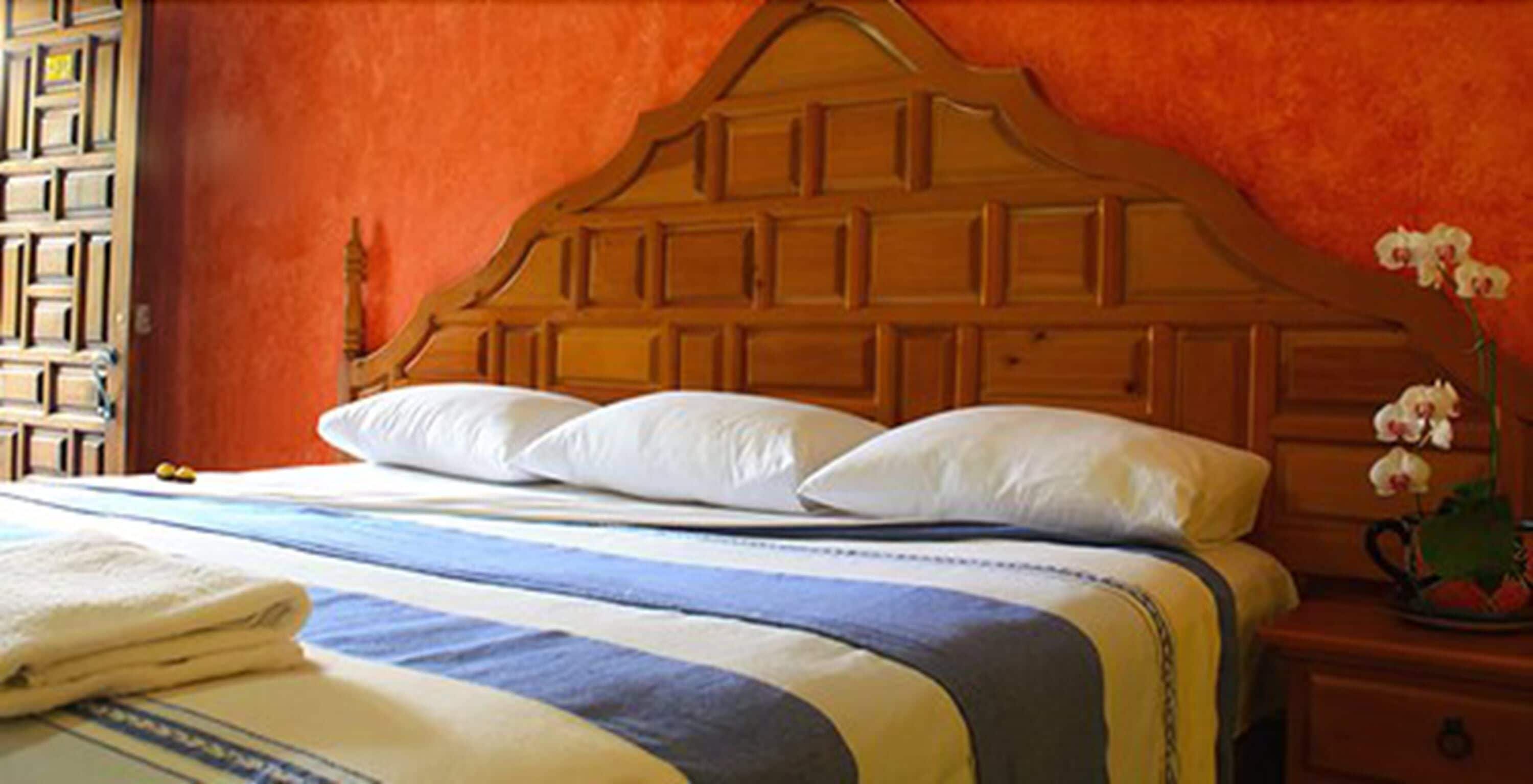 Una cama con cabecera de madera, almohadas blancas y ropa de cama a rayas.