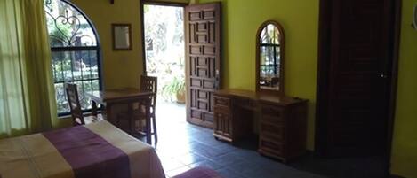 A room with two beds, a desk, a chair, a mirror, and a door.