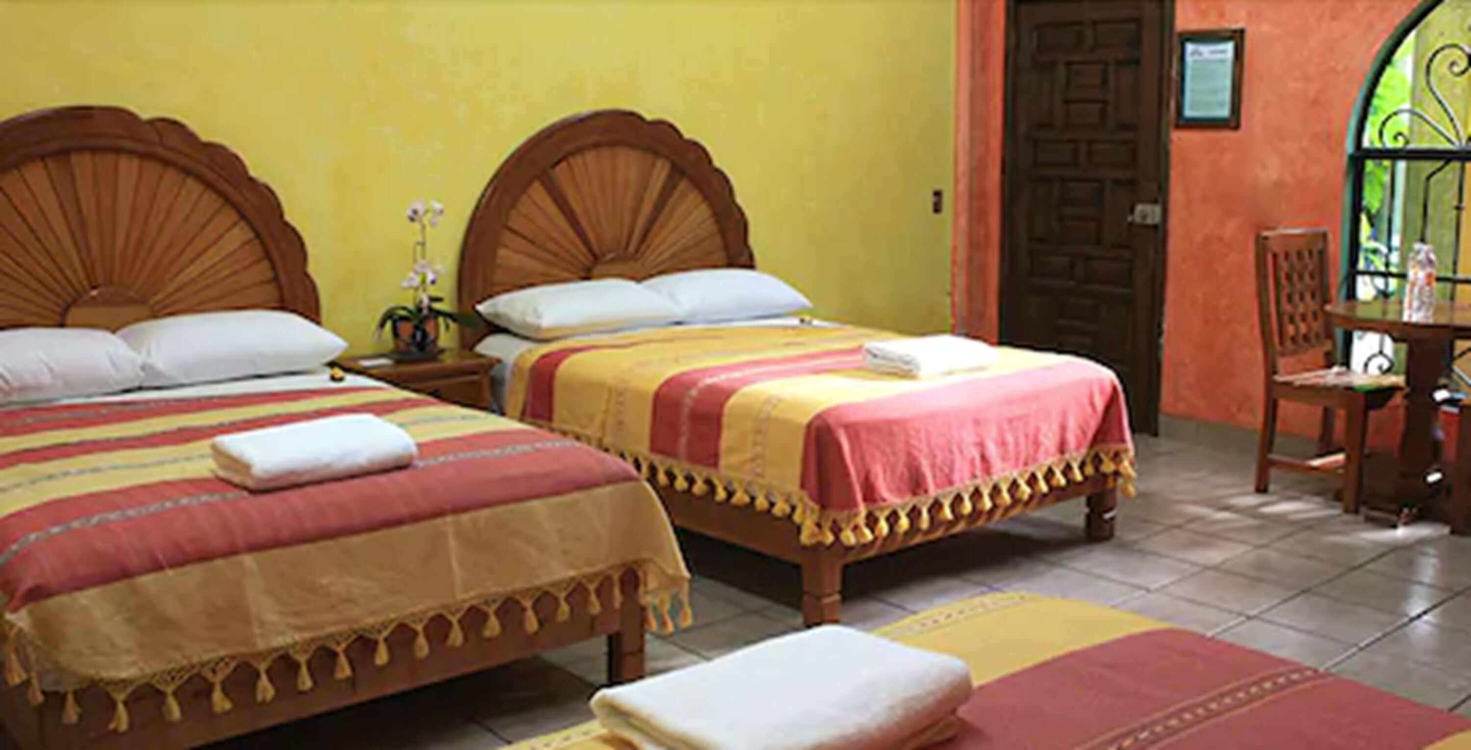Two wooden beds with matching headboards, a small table with a chair, and a door with a window.