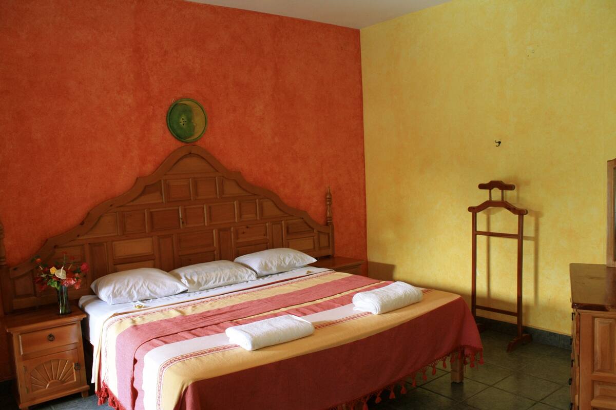 Un dormitorio con una cama de madera, una mesita de noche, un tocador y un espejo.