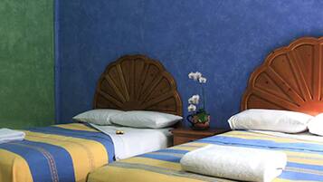 Habitación de hotel con dos camas, cada una con cabecero de madera, almohadas blancas y ropa de cama a rayas.