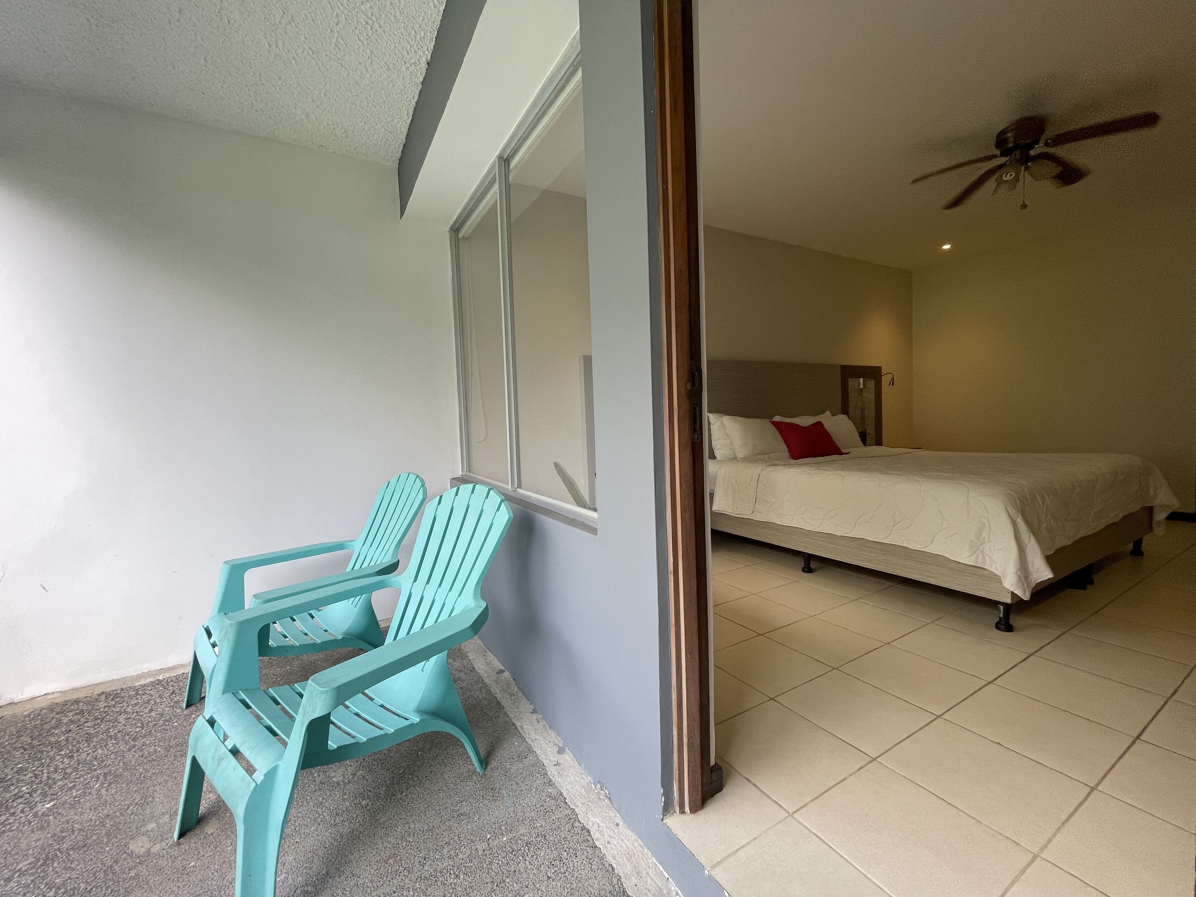 Una camera da letto con un letto, un ventilatore a soffitto e una finestra.