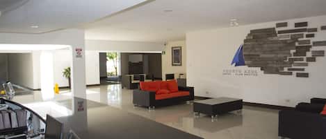 Un vestíbulo moderno con una recepción, un área de descanso y una pared con un logotipo.