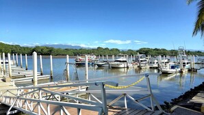 Un puerto deportivo con barcos amarrados, pasarelas de madera y una vista despejada del agua y montañas distantes.