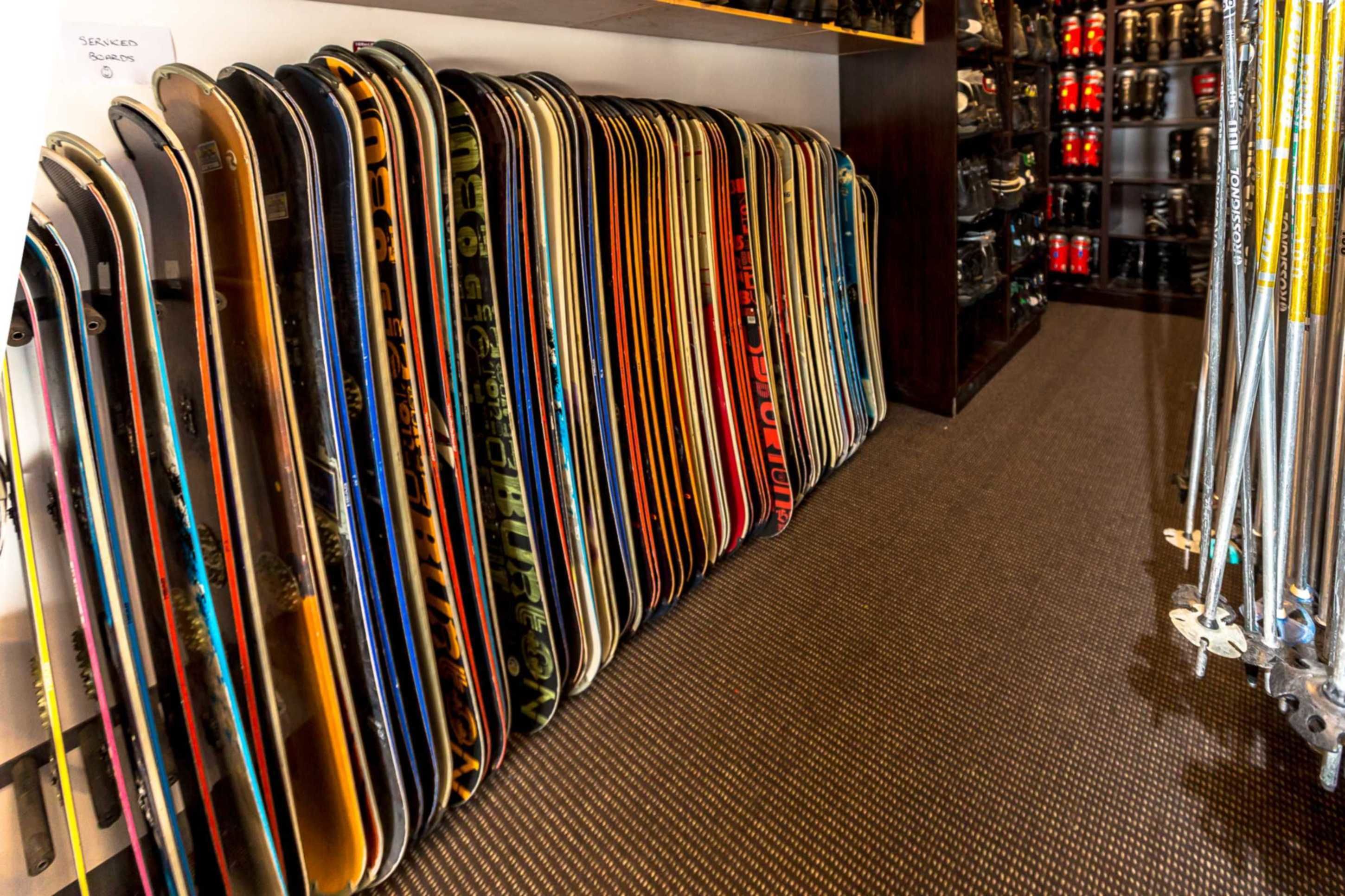 A row of skis and snowboards in a store.