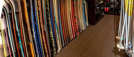 A row of skis and snowboards in a store.