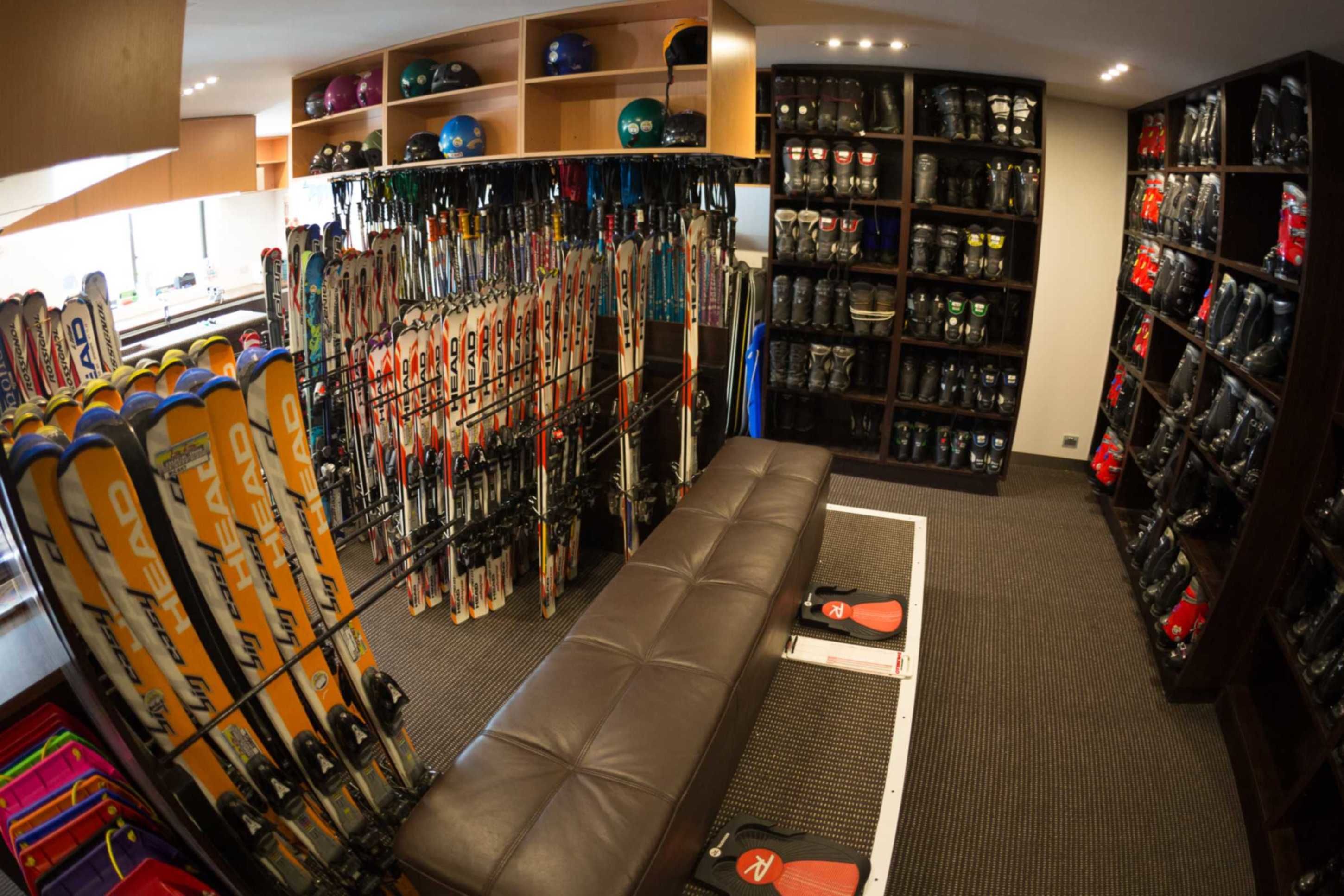 A ski shop with rows of skis, ski boots, helmets, and other gear.