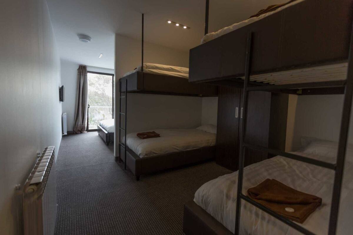 A room with bunk beds, a radiator, a window with curtains, and a door.
