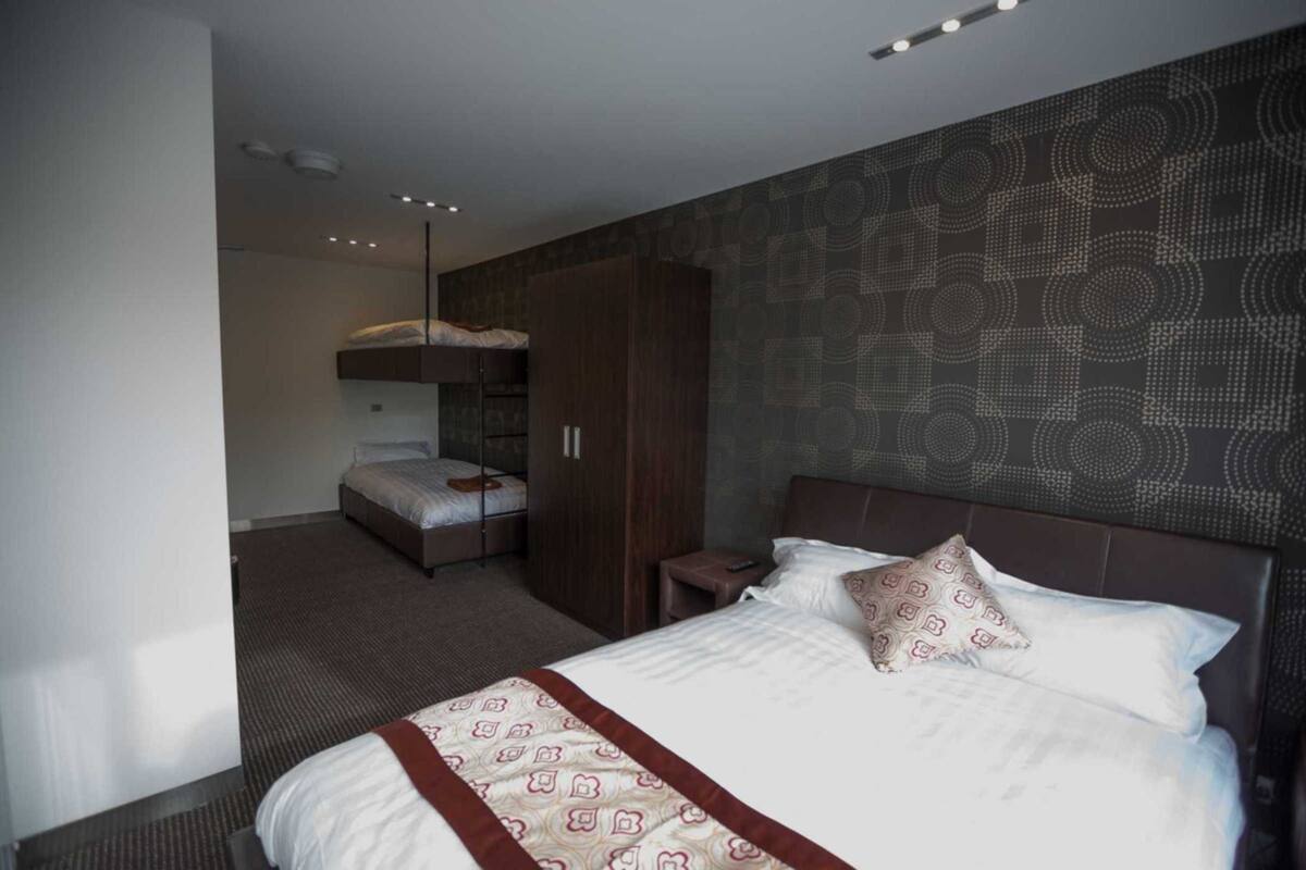 A hotel room with a large bed, a wardrobe, and a bunk bed.