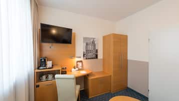 Ein Hotelzimmer mit Schreibtisch, Stuhl, Fernseher, Kleiderschrank und Bett.
