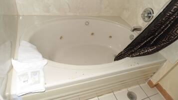 A bathroom with a bathtub, a shower curtain, and a white towel.