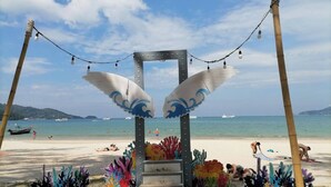 Una playa con un arco decorativo adornado con motivos de coral de colores y luces colgantes.