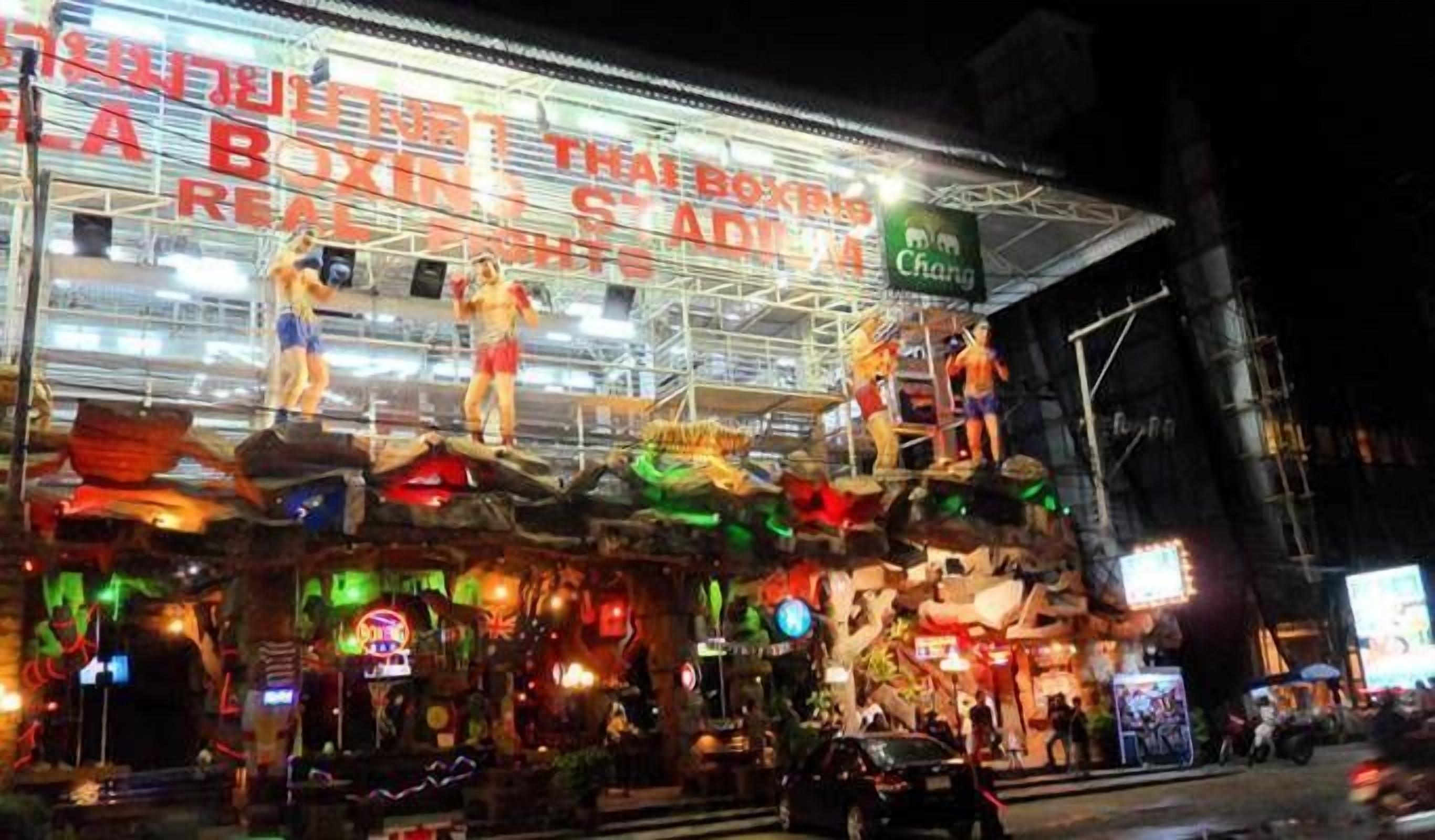 A brightly lit building with a sign reading "Thai Boxing Stadium."