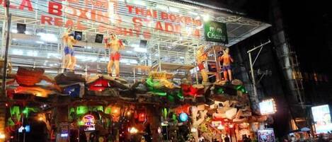 A brightly lit building with a sign reading "Thai Boxing Stadium."