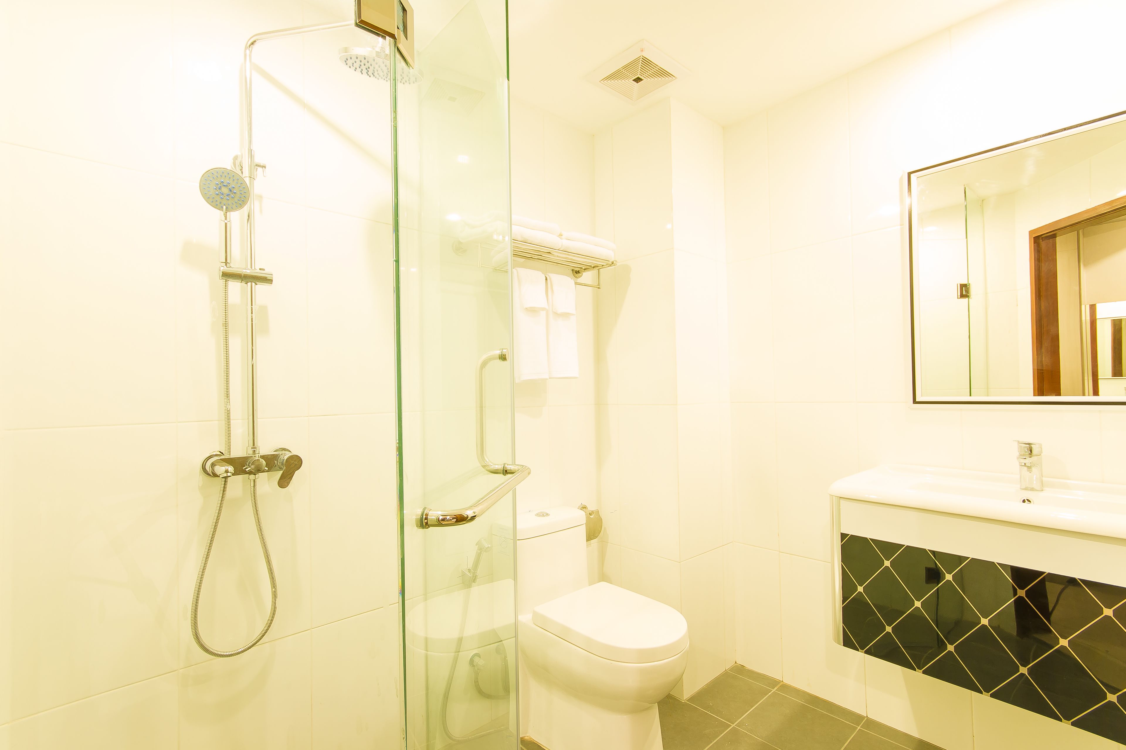 A bathroom with a glass-enclosed shower, a white toilet, and a sink with a black tiled backsplash.