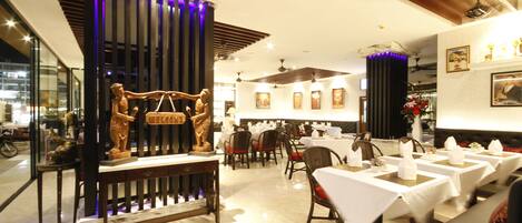 A restaurant with a central reception area, multiple dining tables, and chairs.