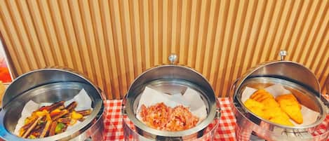Three metal bowls with food on a checkered tablecloth.