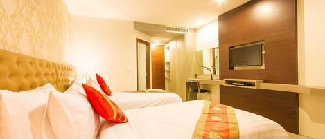 A hotel room with a large bed, a desk, a television, and a wardrobe.