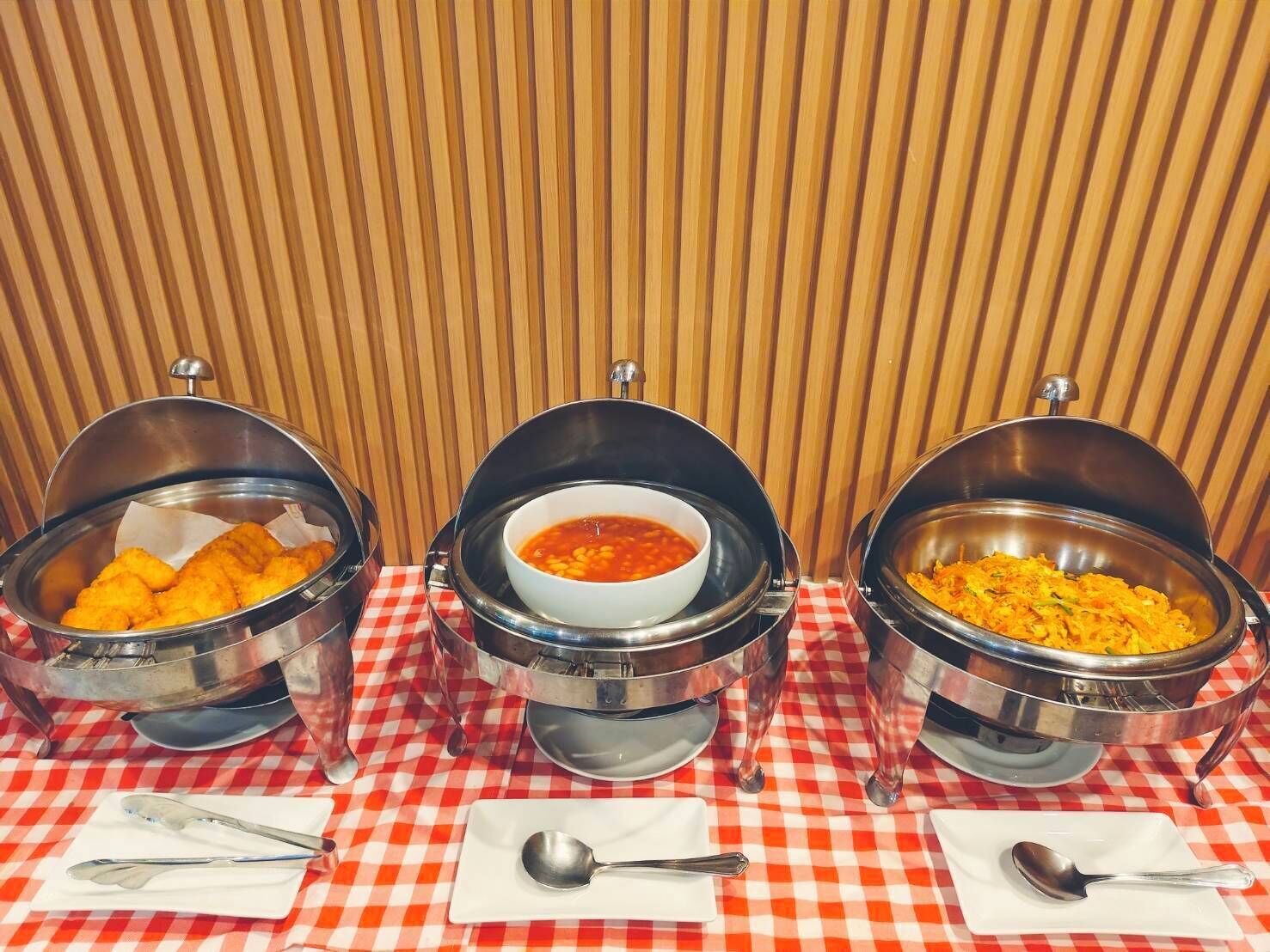 Drie opspuitbare dispensers met een geruit tafelkleed, elk gevuld met verschillende gerechten.
