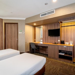 Habitación de hotel con dos camas, un escritorio, una silla, un televisor y un minibar.